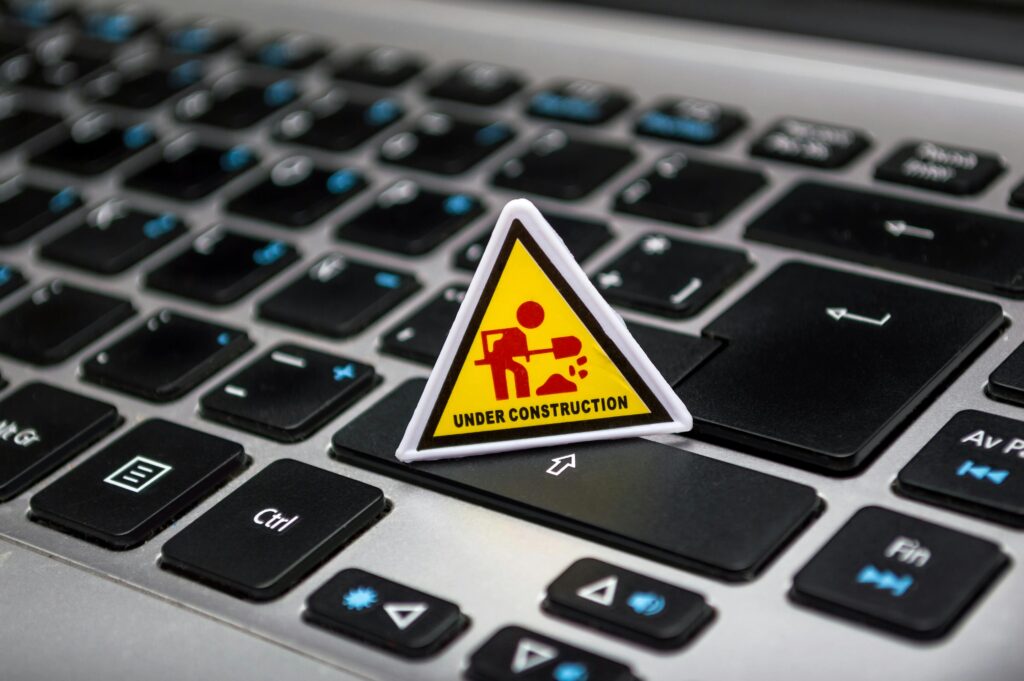A miniature under construction sign placed on a laptop keyboard symbolizing digital development.